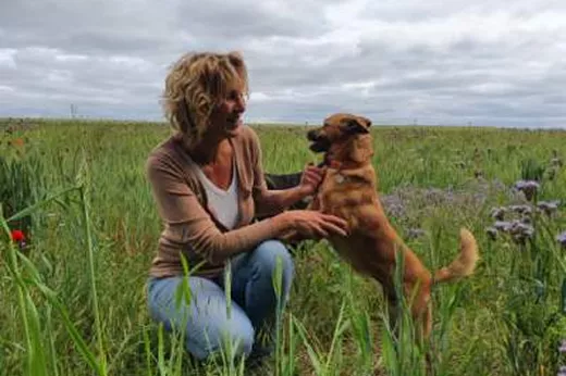 Muriel jouant avec son chien dans un champ, moment complice