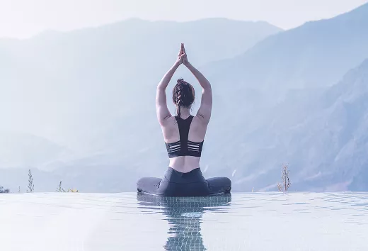 Femme en méditation face aux montagnes, mains jointes